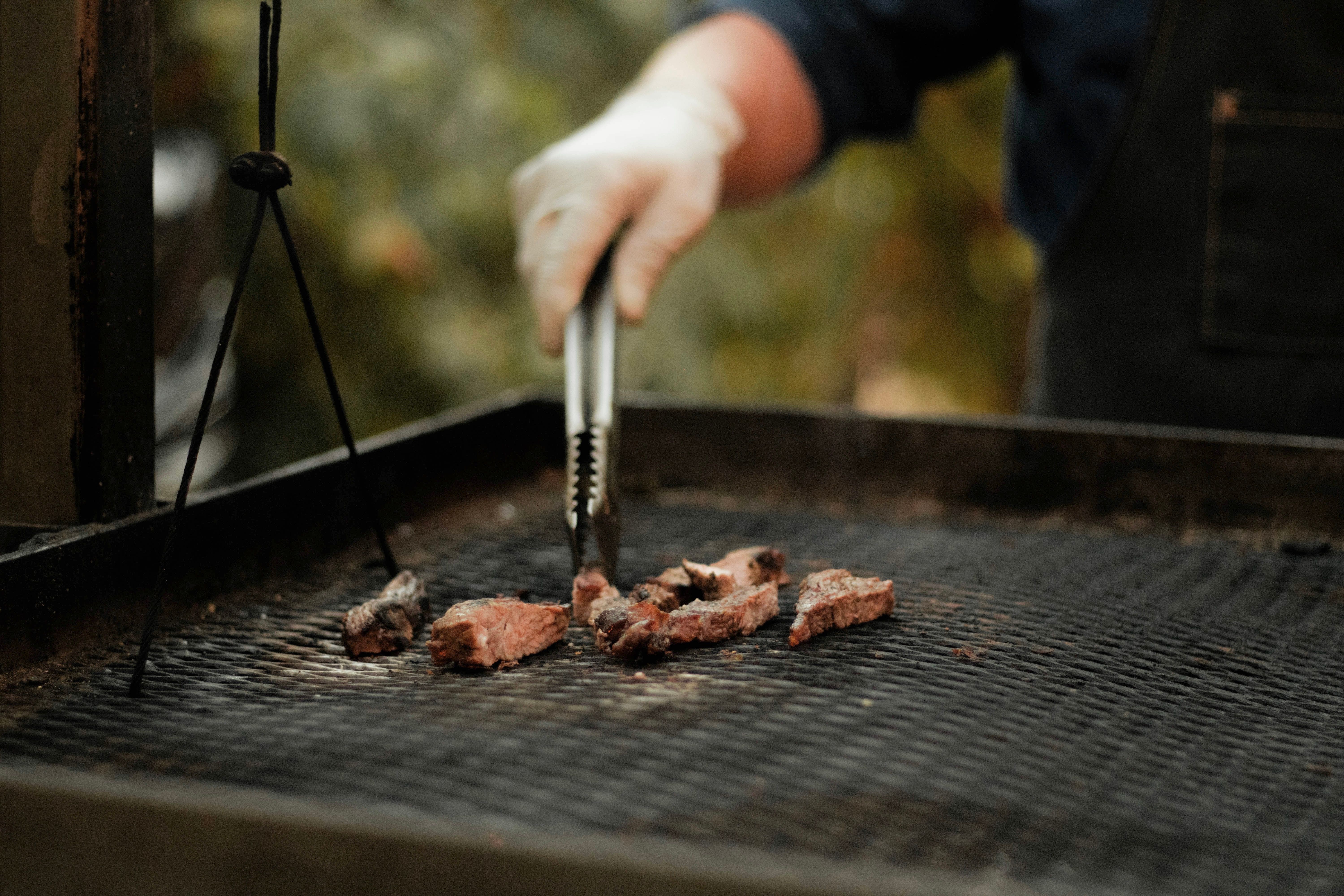Close view of food being turned on an outdoor barbecue