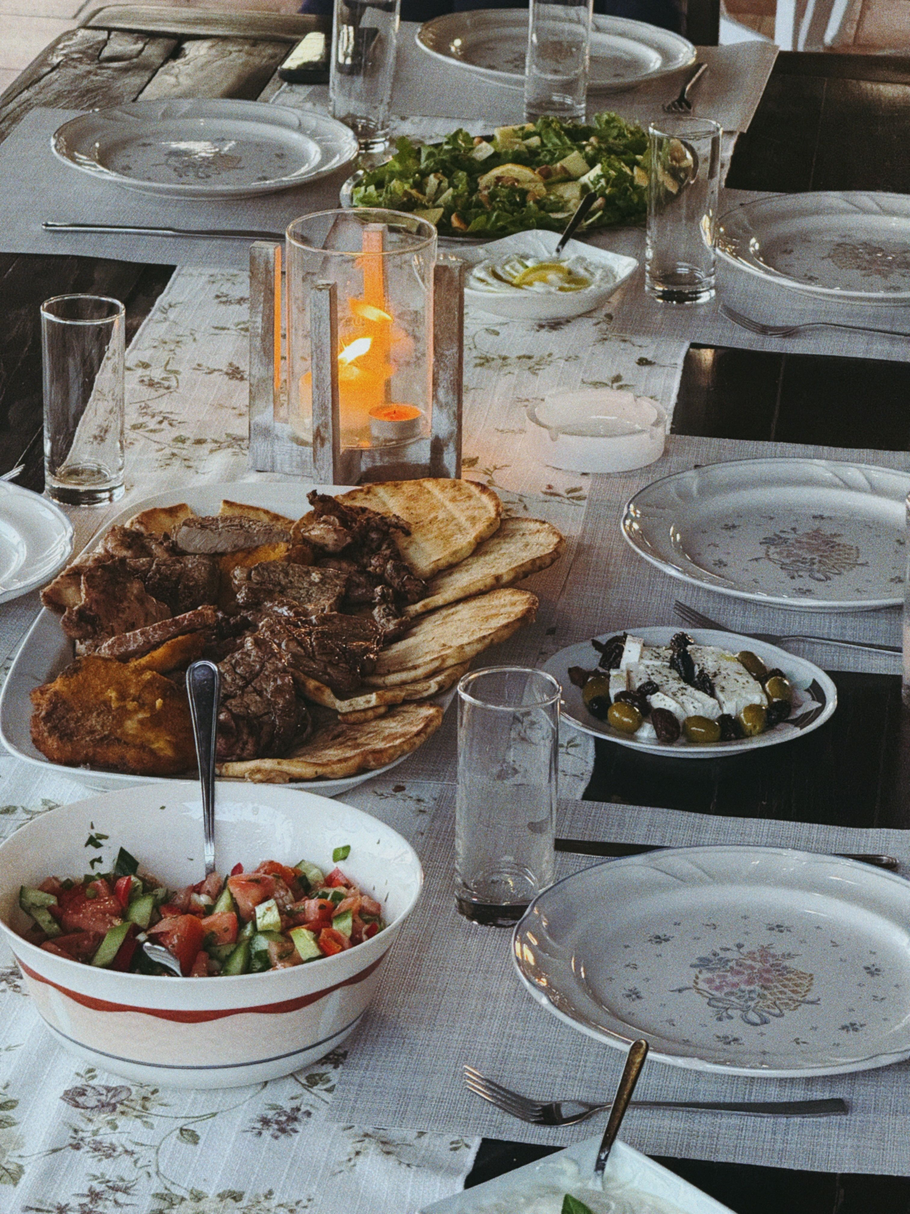 Greek-style shared table with grilled food, salads and bread